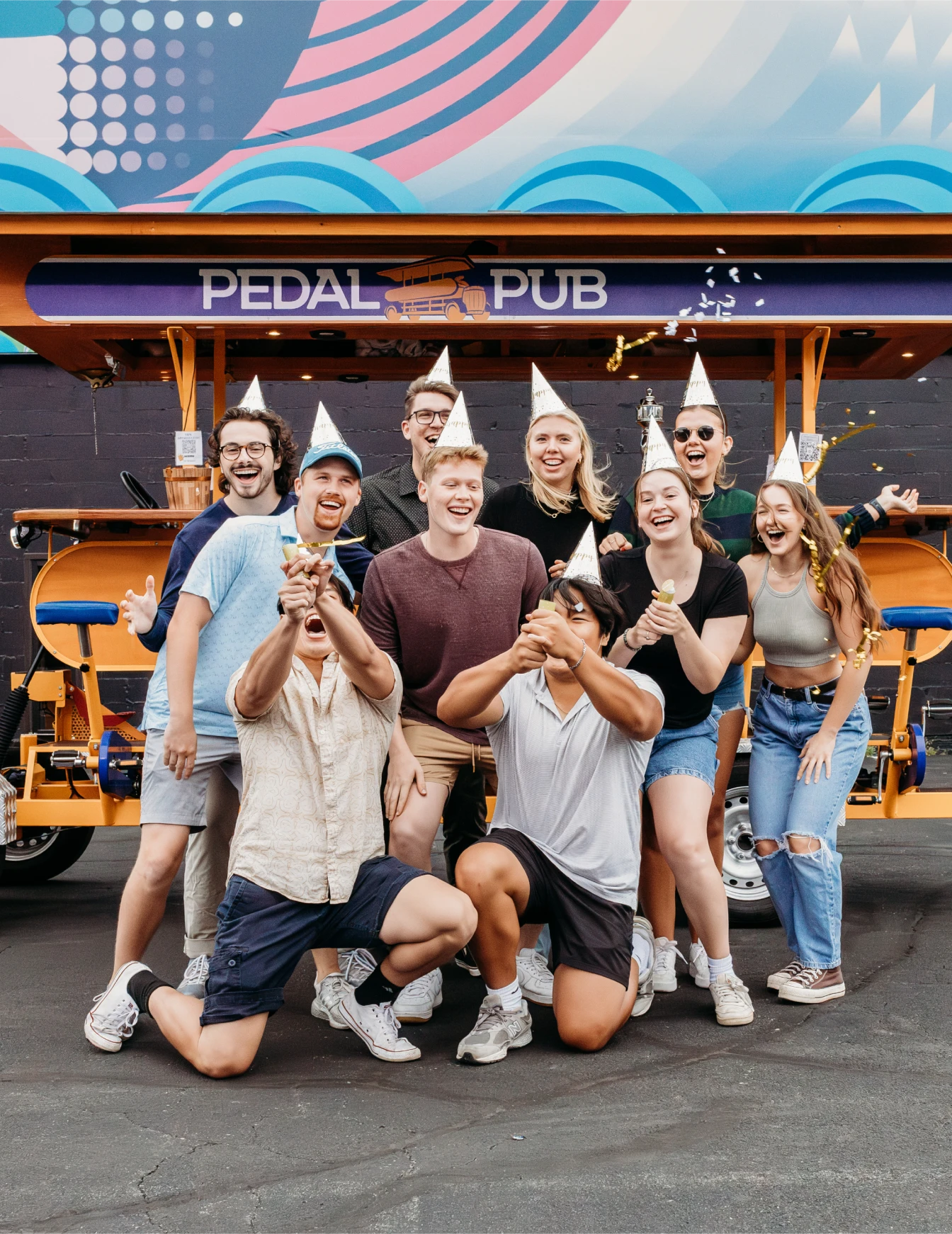 friends with birthday caps posing in front of Pedal Pub